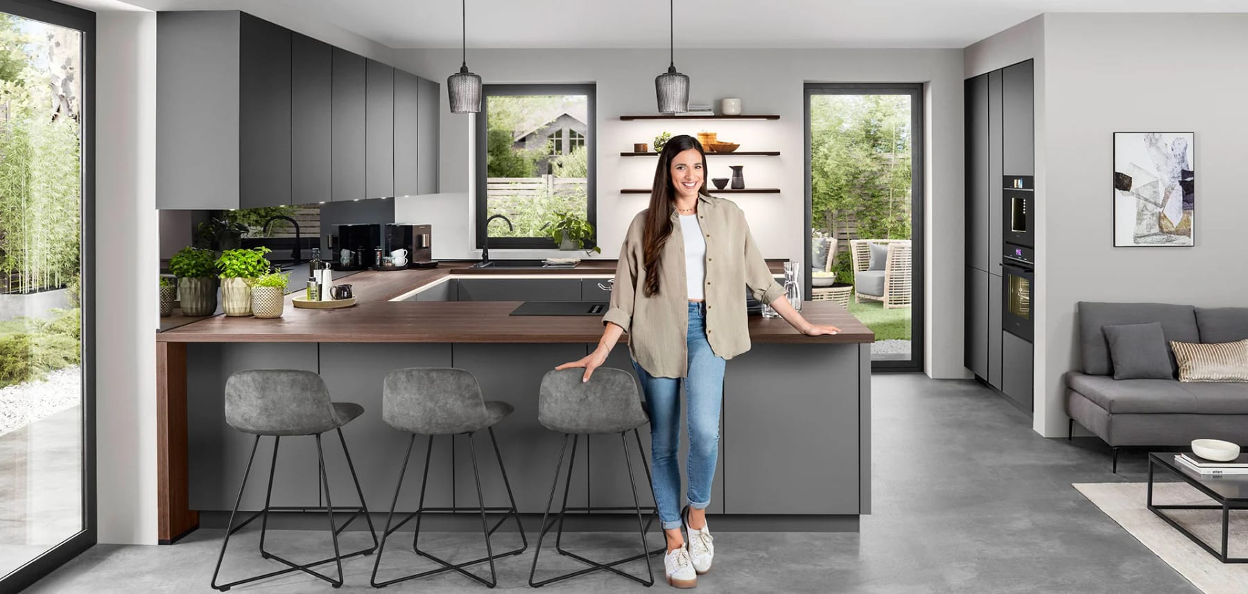 Cuisine grise ouverte sur le séjour, péninsule prolongée d’un plan de travail décor noyer et de trois tabourets