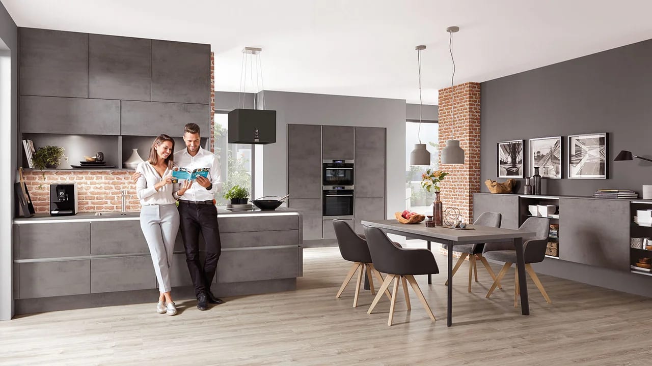 Cuisine en décor béton gris avec mur de brique apparente et îlot central