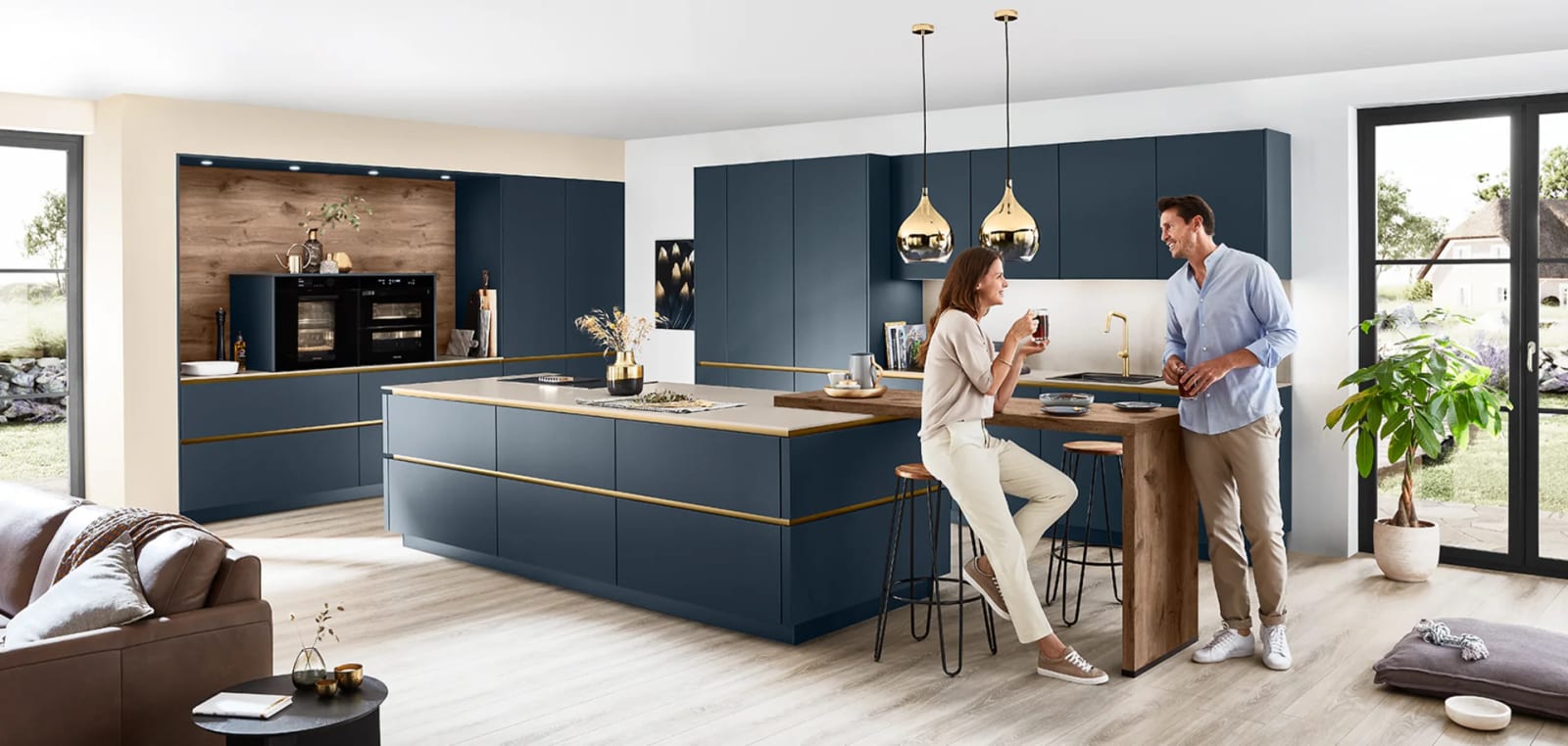 Cuisine sans poignée en laque ultra-mate bleu profond, gorges dorées courant sous chaque rangée, îlot et table haute en bois