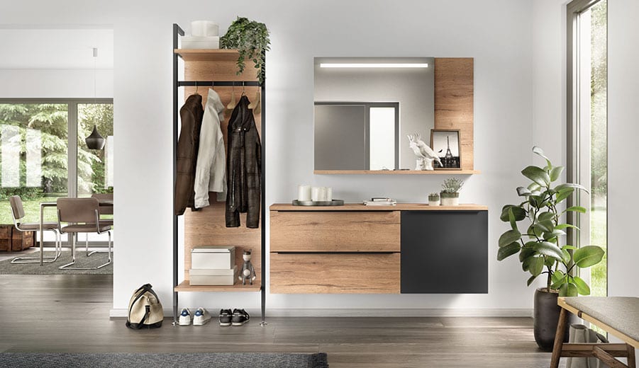 Entrée en décor chêne et gris anthracite : vestiaire ouvert sur montants noirs avec tringle et manteaux, meuble suspendu à tiroirs, miroir éclairé et tablette d’appoint