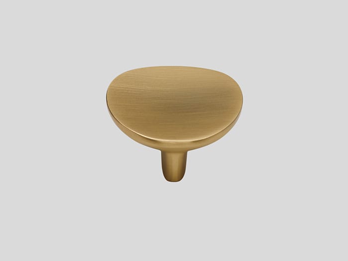 Bouton de meuble en métal doré jaune, tête ovale bombée, vue de face sur fond gris