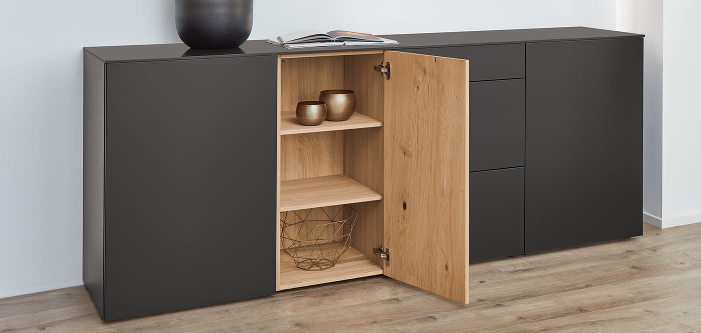 Meuble haut anthracite entrouvert sur un intérieur en placage de chêne, rangement discret