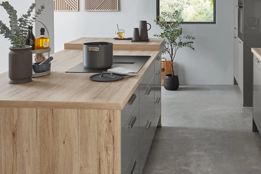 Îlot dont la joue en décor chêne clair descend jusqu’au sol dans la teinte de son plan de travail, façades grises brillantes