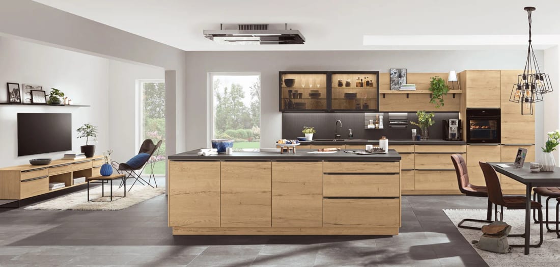 Cuisine à îlot en décor chêne clair, plan de travail en décor béton noir et séjour dans le prolongement