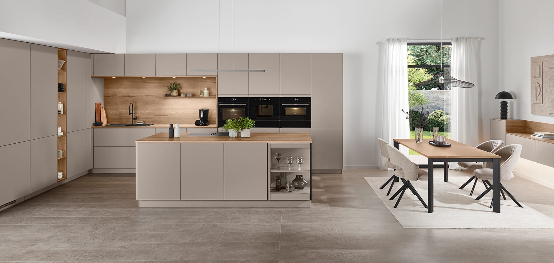 Cuisine taupe sans poignée ouverte sur une salle à manger, îlot central et crédence en décor chêne